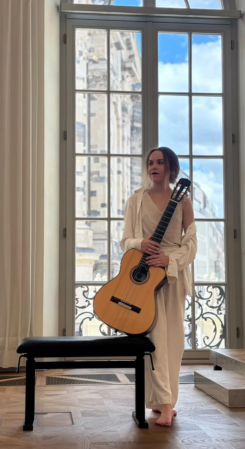 Margaréta Lakner mit ihrer Gitarre an einem hohen Fenster mit Blick über Dresden